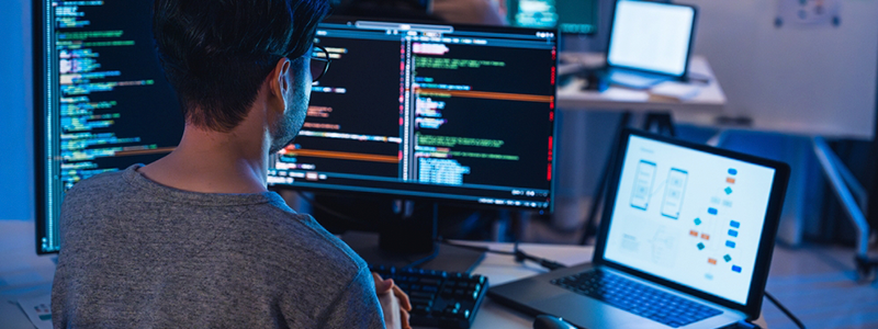 Man sitting at computer with Software development software on computer